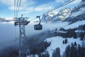 Gondel Aufzug ziehen um Über Wald inmitten schneebedeckt Berge foto