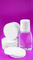 Weiß Behälter mit Kosmetika Gesicht Creme, Hand Creme, Mineral Wasser, Baumwolle Pads auf Weiß Rosa, vereinbart worden vertikal foto