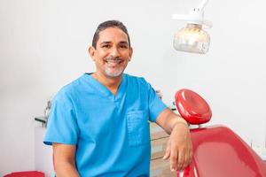 Porträt von ein männlich Mitte -alt Zahnarzt beim seine Büro foto