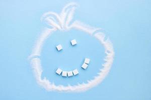Zucker Gesicht Lächeln von Zucker Würfel ohne einer Zahn auf ein Blau Hintergrund, Müll Essen foto
