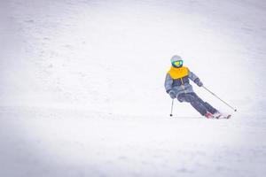 Low Angle Vorderansicht männliche Person allein Skifahren bergab foto