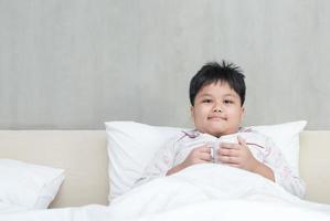 Fett Junge mit Milch Tasse auf Schlafzimmer foto