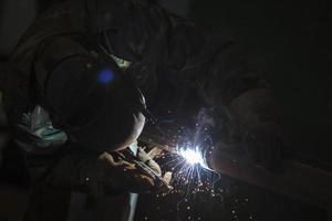 Schweißer beim arbeiten. Mann im ein schützend Maske. das Schweißer macht Nähte auf das Metall. Funken und Rauch wann Schweißen. foto