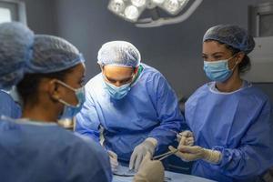 OP-Team, das Operationen in einem modernen Operationssaal durchführt, Ärzteteam, das sich während einer Operation auf einen Patienten konzentriert, Ärzteteam, das während einer Operation im Operationssaal zusammenarbeitet, foto