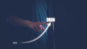 Geschäft planen und Strategie Konzept, Mann Hand Zeichnung Linie zum zunehmend Pfeil von 2023 zu 2024 zum Vorbereitung glücklich Neu Jahr Konzept. Neu Geschäft im Neu Jahre, Start oben foto