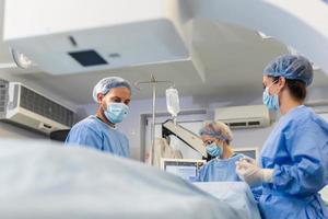 Chirurgen mit chirurgisch Maske beim Betriebs Zimmer mit 3d Bild geführt Chirurgie Maschine foto
