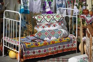 Antiquität ethnisch Bett mit Kissen und Tagesdecken gestickt mit ein slawisch Muster. foto