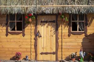 Hintergrund Holz Mauer von ein Haus mit ein Fenster und ein mit Stroh gedeckt Dach. foto