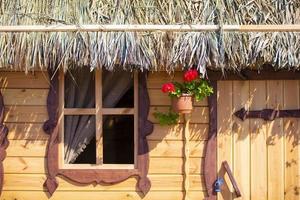 Hintergrund Holz Mauer von ein Haus mit ein Fenster und ein mit Stroh gedeckt Dach. foto