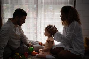 Eltern und Kinder entspannen im das Leben Zimmer von das Haus. Uhr Baby glücklich abspielen mit seine Liebling Spielzeug. foto