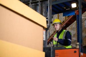 Arbeiter im Auto Teile Warenhaus verwenden ein Gabelstapler zu Arbeit zu bringen das Box von Auto Teile in das Lager Regal von das Warenhaus warten zum Lieferung zu das Auto Versammlung Linie foto