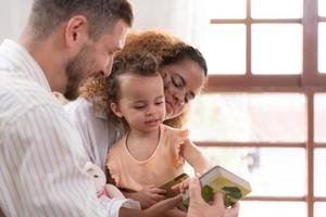 Eltern und Kinder entspannen im das Leben Zimmer von das Haus. Uhr Baby glücklich abspielen mit seine Liebling Spielzeug. foto