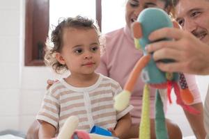 Eltern mit wenig Mädchen haben Spaß spielen mit Ihre Neu Spielzeuge im das Schlafzimmer zusammen. Spielzeuge Das verbessern Kinder- Denken Fähigkeiten. foto