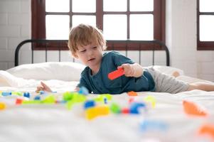 wenig Junge im seine Schlafzimmer mit ein Neu Spielzeug gekauft durch seine Eltern zu Hilfe ihm verbessern seine Denken Fähigkeiten. foto