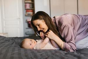 glücklich Mutter haben Spaß und Lachen mit ihr Baby auf das Bett foto