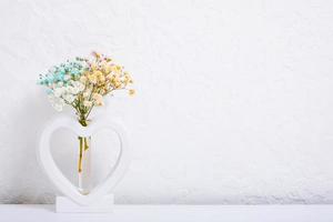 Vase Herzform mit mehrfarbig Gypsophila Blumen auf Weiß. minimalistisch Innere Dekor mit Kopieren Raum foto