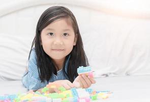 süß asiatisch Mädchen abspielen Block Ziegel auf Bett foto