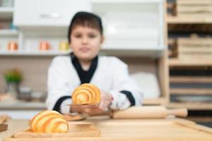 Porträt von ein wenig Junge im das Küche von ein Haus haben Spaß spielen Backen Brot foto