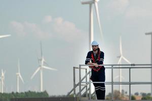 Ingenieur beim natürlich Energie Wind Turbine Seite? ˅ mit ein Mission zu steigen oben zu das Wind Turbine Klingen zu prüfen das Betrieb von groß Wind Turbinen Das konvertiert Wind Energie in elektrisch Energie foto