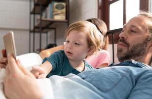 wenig Jungs Vater lesen Geschichten zu Kinder Vor gehen zu Bett zu entspannen und Schlaf solide bis um das Morgen. foto