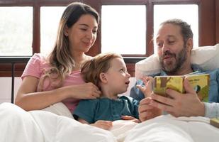 wenig Jungs Vater lesen Geschichten zu Kinder Vor gehen zu Bett zu entspannen und Schlaf solide bis um das Morgen. foto