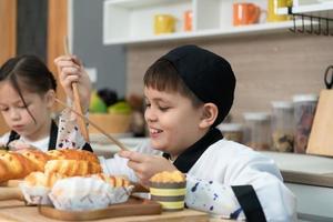 Porträt von ein wenig Mädchen und Junge im das Küche von ein Haus haben Spaß spielen Backen Brot foto