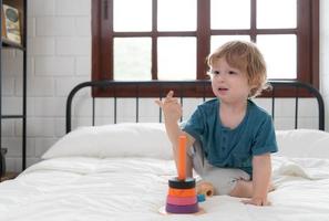 wenig Junge im seine Schlafzimmer mit ein Neu Spielzeug gekauft durch seine Eltern zu Hilfe ihm verbessern seine Denken Fähigkeiten. foto