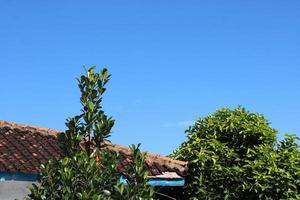 Foto von das Blau Himmel über das Dach Fliesen von das Haus