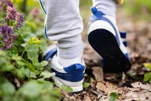 Junge Beine tragen Turnschuhe Gehen auf Wald Pfad. draussen Frühling Freizeit Konzept. foto