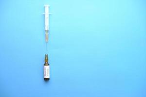 Covid-19-Impfstoff und Spritze auf blauem Hintergrund foto