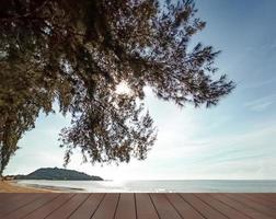 leeren hölzern Deck mit Meer Aussicht und Kiefer Baum auf das Strand. schließen oben alt hölzern Bodenbelag und tropisch Strand. foto