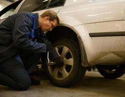 Fachmann Garage Mechaniker Reparatur das undicht Reifen Auto Räder. Auto Ingenieur Techniker Ändern ein Auto Reifen auf ein Fahrzeug. Konzept von Bedienung oder Ersatz, Auto Reparatur und Instandhaltung foto