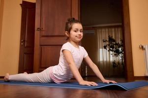 wenig Mädchen üben Yoga, Dehnen im urdhva Mukha shvanasana Übung, nach oben gegenüber Hund Pose, lächelnd beim Kamera foto