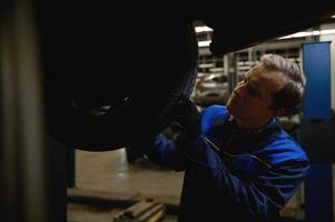 Nahansicht von ein Mechaniker Überprüfung Reifen im Instandhaltung Bedienung Center. Techniker oder Ingenieur Fachmann Arbeit zum Kunde, Auto Reparatur Konzept foto