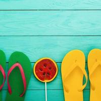 Sommer Accessoires. Flip Flops, Sonnenbrille, Handtuch, rote Mütze und Orangen auf blauem Holzhintergrund. Platz kopieren. foto