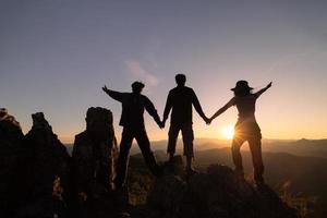 Silhouetten von drei Menschen Klettern auf Berg und Portion. Hilfe und Hilfe Konzept. foto