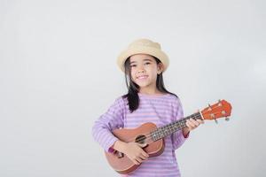 süß wenig Mädchen im Badeanzug spielen Ukulele. glücklich Ferien Konzept. foto