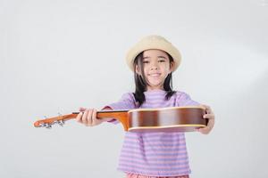 süß wenig Mädchen im Badeanzug spielen Ukulele. glücklich Ferien Konzept. foto