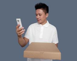 Mann suchen beim Zelle Telefon Bildschirm halten Karton Box foto
