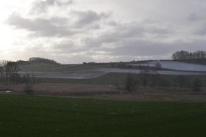 Schnee auf das Hügel mit ein nass Grün Senke foto