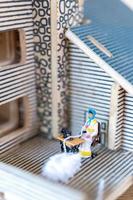 Miniaturmenschen, Frau, die an einer Nähmaschine in ihrem Haus näht. weibliche Näherin, die an einer Nähmaschine arbeitet