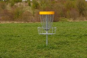 Rabatt Golf Korb. Frisbeescheibe Golf ist Sport und Hobbie im draussen Park. Metall Korb mit Ketten zum Rabatt Spiel umgeben durch beschwingt Grün Bäume. foto