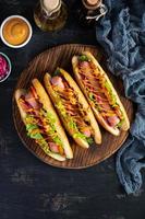 heiß Hund mit Kopfsalat, Tomaten und eingelegt Zwiebeln. gegrillt Brötchen mit Würstchen foto