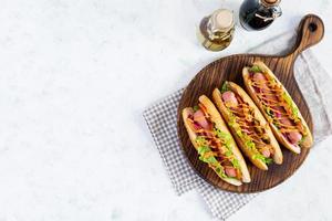 heiß Hund mit Kopfsalat, Tomaten und eingelegt Zwiebeln. gegrillt Brötchen mit Würstchen foto