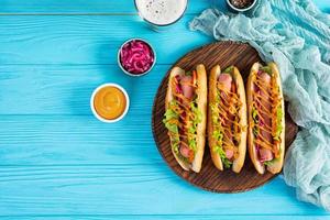 heiß Hund mit Kopfsalat, Tomaten und eingelegt Zwiebeln. gegrillt Brötchen mit Würstchen foto