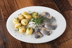 Hering Fisch mit jung Kartoffeln Bälle auf ein Weiß Teller foto