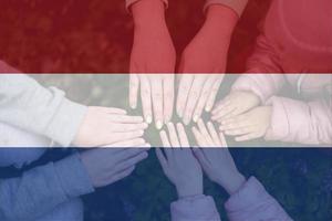 Hände von Kinder auf Hintergrund von Niederlande Flagge. Niederländisch Patriotismus und Einheit Konzept. foto