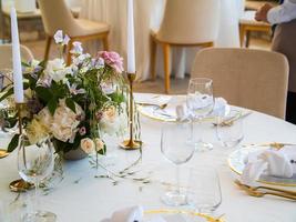 schön draussen Hochzeit Dekoration im Stadt. Kerzen und getrocknet Blumen und Zubehör mit Blumensträuße und Brille auf Tabelle mit Leinen- Tischdecke auf frisch verheiratet Tabelle auf Grün Rasen foto