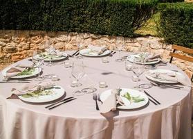 schön draussen Hochzeit Dekoration im Stadt. Kerzen und getrocknet Blumen und Zubehör mit Blumensträuße und Brille auf Tabelle mit Leinen- Tischdecke auf frisch verheiratet Tabelle auf Grün Rasen foto