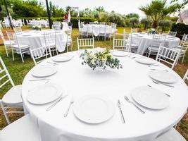 schön draussen Hochzeit Dekoration im Stadt. Kerzen und getrocknet Blumen und Zubehör mit Blumensträuße und Brille auf Tabelle mit Leinen- Tischdecke auf frisch verheiratet Tabelle auf Grün Rasen foto